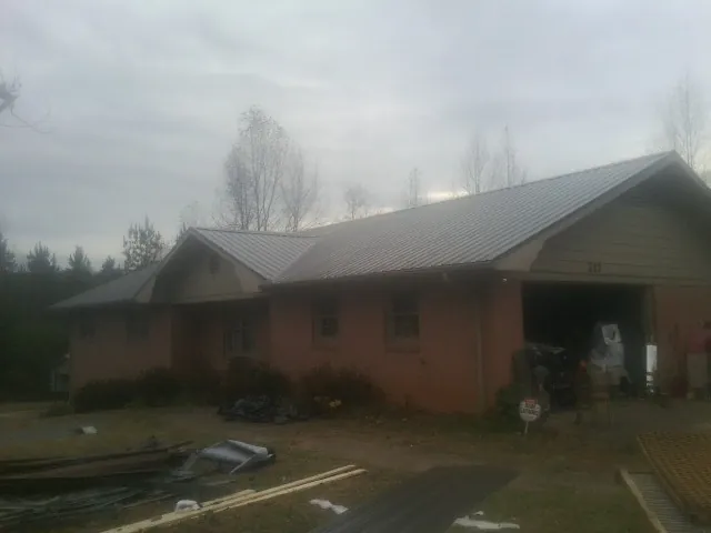 Gray metal roof on a stucco house with an attached garage in Edgerton