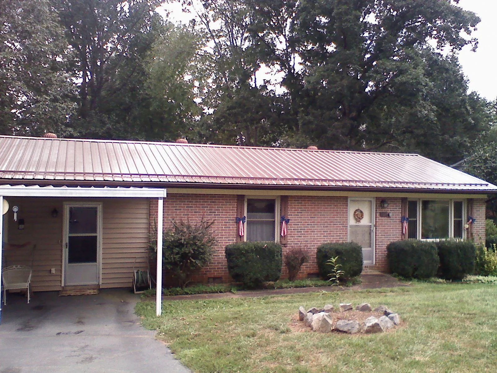 Bronze metal roof and carport on a brick ranch home — Roof Repair work by our crew in Edgerton