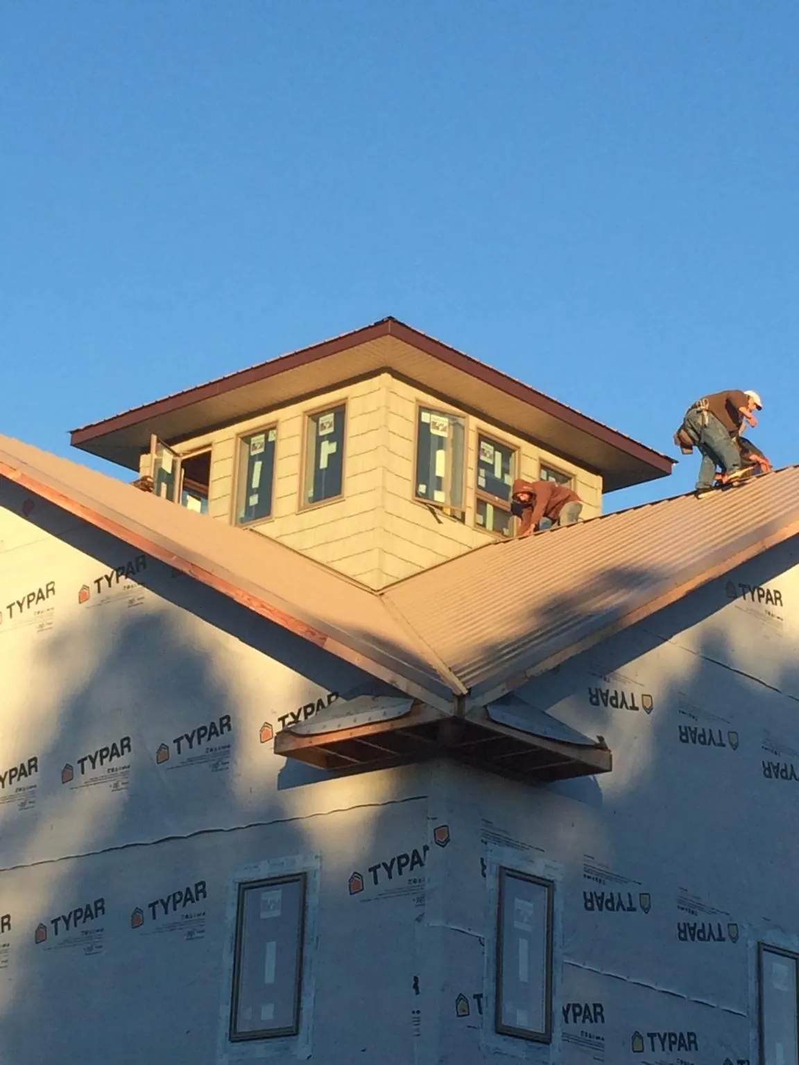 Roofers working around a rooftop cupola on a new metal roof at sunset — Roof Waterproofing in Edgerton by Roofing Brothers